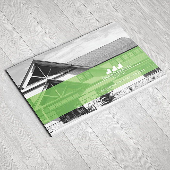 A green and white brochure is sitting on a wooden table.
