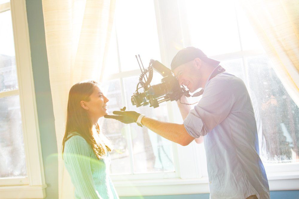 A man is holding a butterfly in front of a woman 's face.