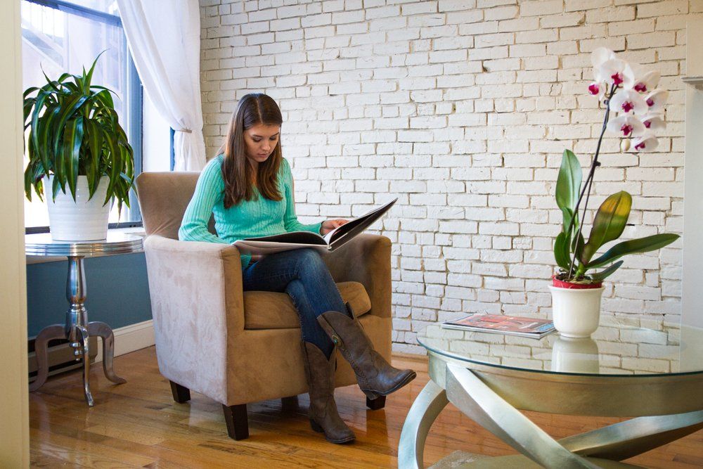 A woman is sitting in a chair reading a book.