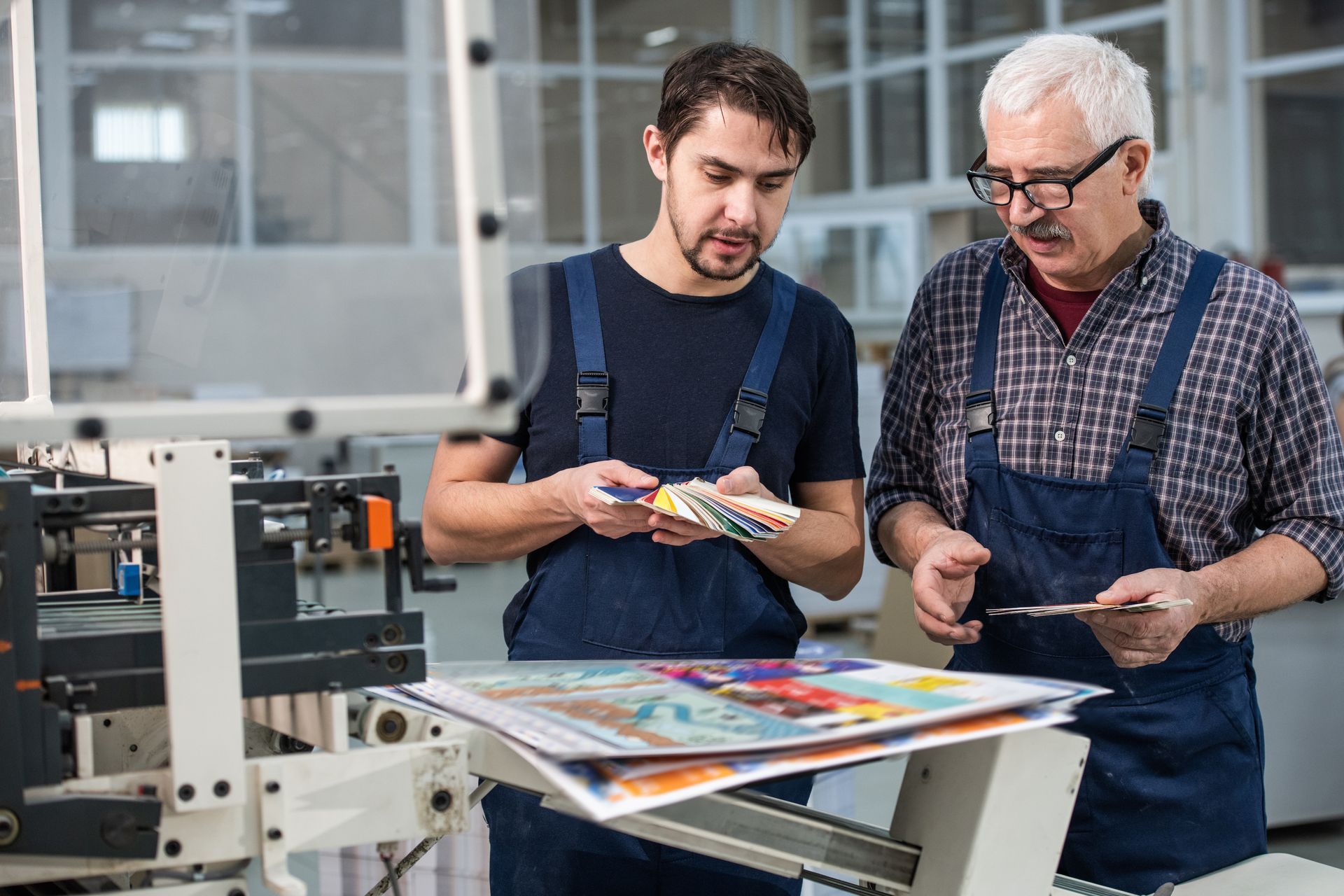 Two men are looking at a piece of paper in a factory.