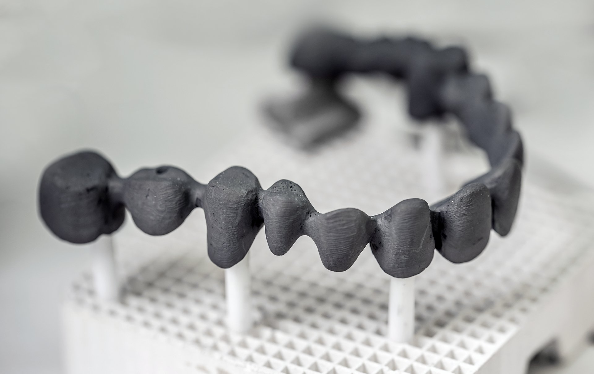 A close up of a 3d printed dental bridge on a table.
