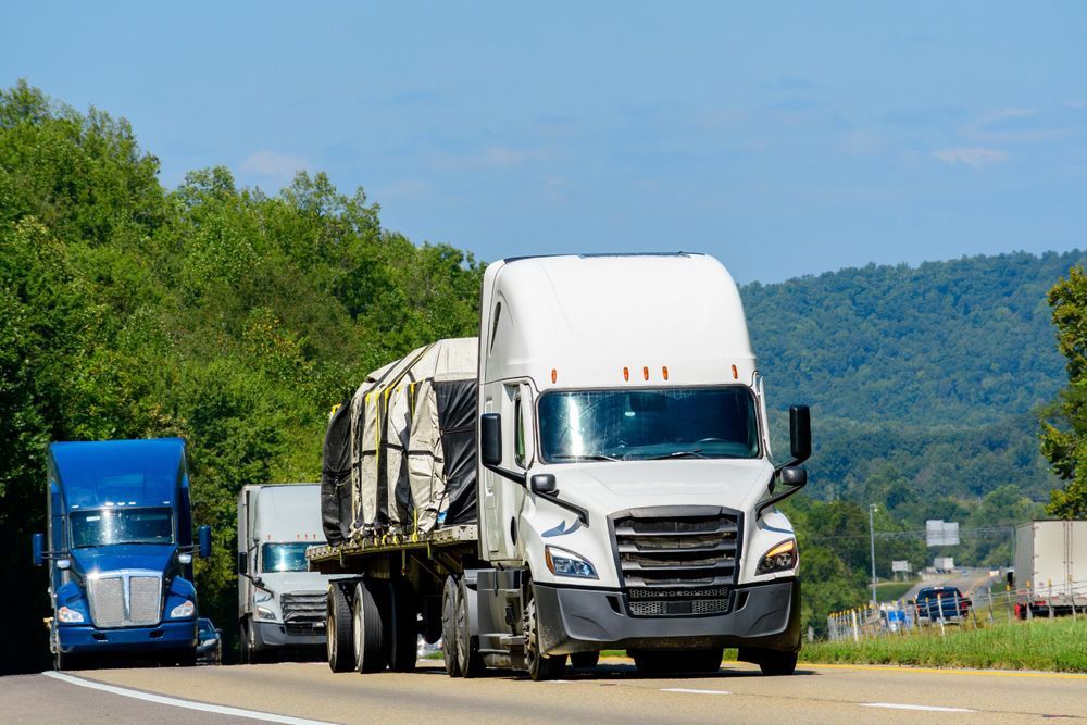 A row of semi trucks are driving down a highway.
