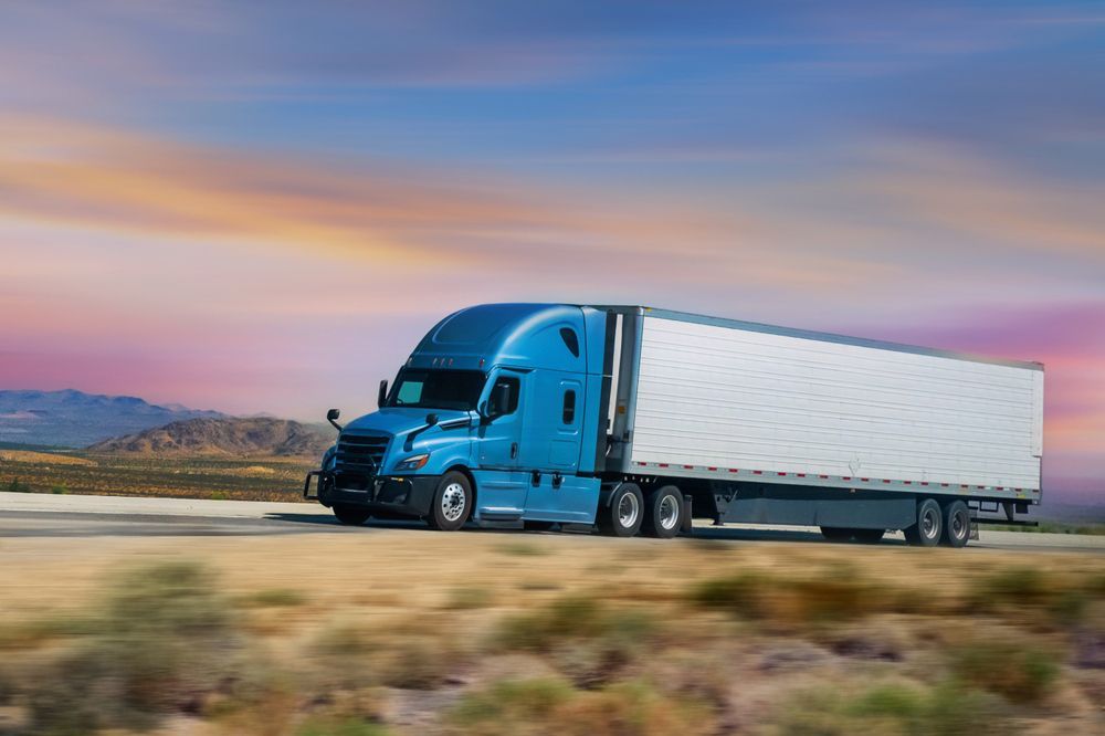 A blue semi truck is driving down a desert highway.