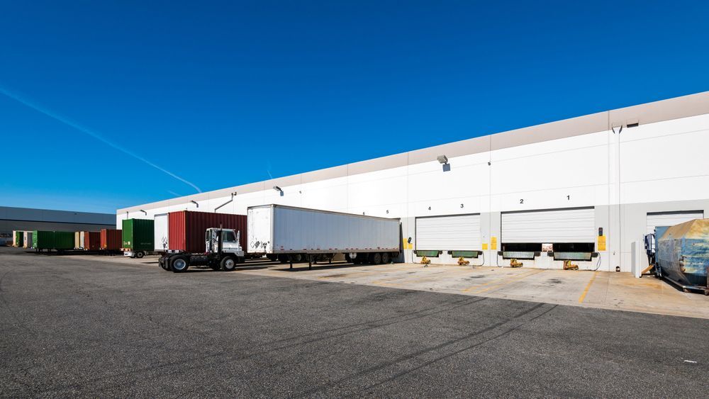 A row of trucks are parked in front of a warehouse.