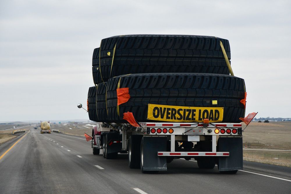 A semi truck is carrying a stack of tires on a highway.