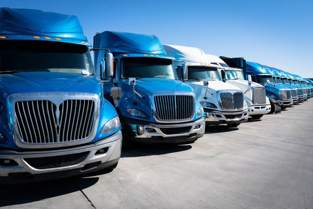 A row of semi trucks are parked in a parking lot.