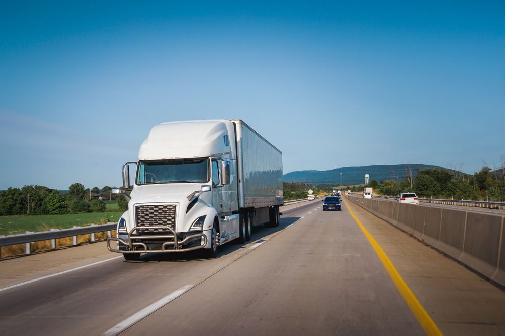 A white semi truck is driving down a highway.