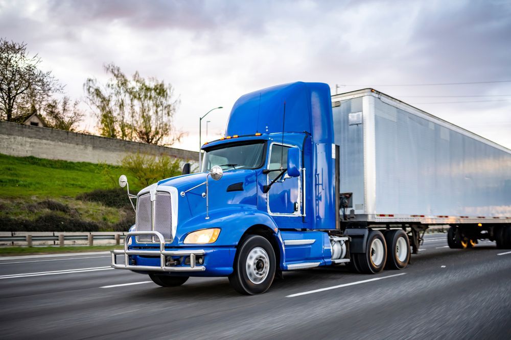 A blue semi truck is driving down a highway.