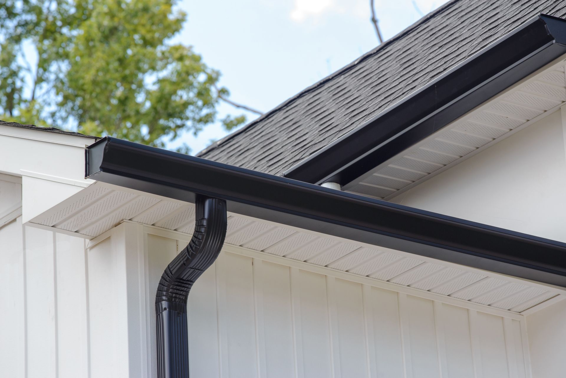 A close up of a black gutter on the side of a house.