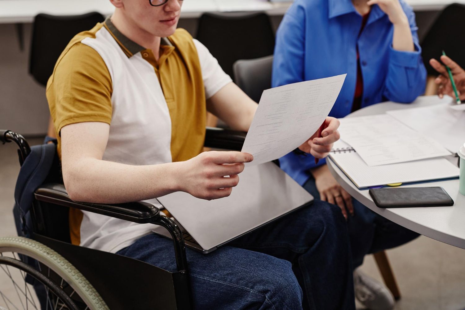 Two people seated at a table reviewing papers in a meeting room