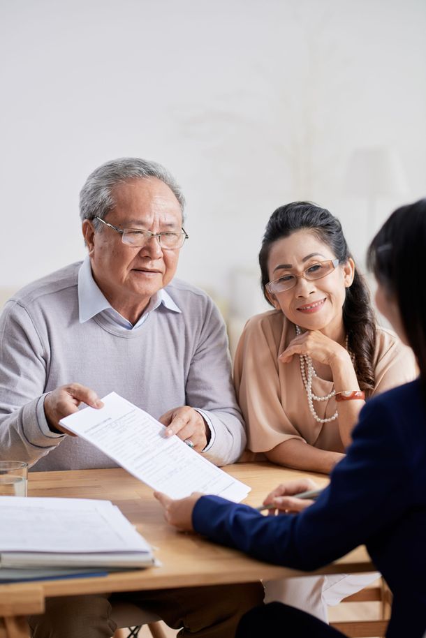 Three people reviewing documents at a table in a bright office meeting room