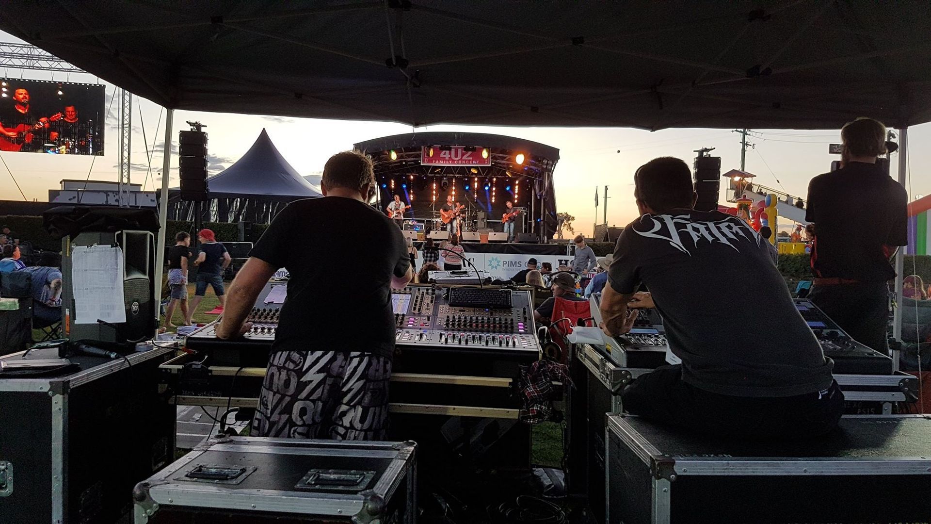 People Working Sound At An Outdoor Concert, Stage In Background — Kennedy Amplifier Hire Service In South Mackay, QLD