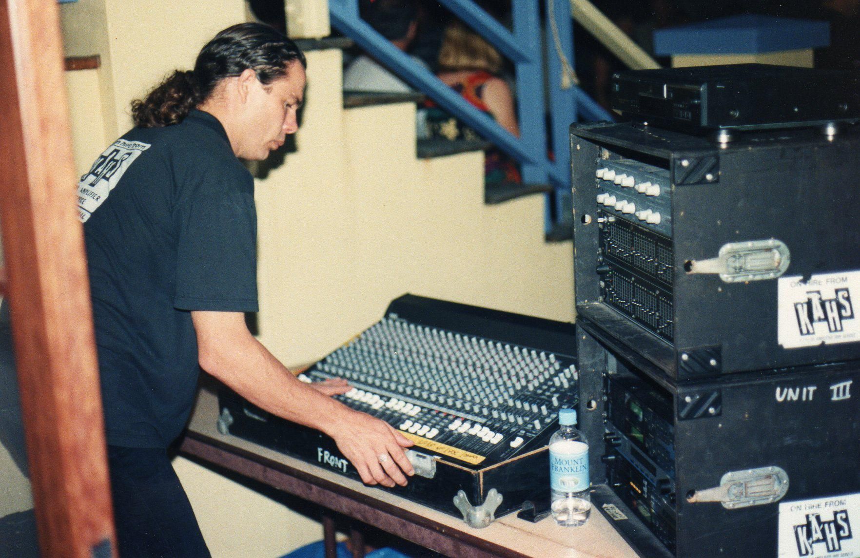 Man Adjusting A Sound Mixing Console Next To Equipment Cases — Kennedy Amplifier Hire Service In South Mackay, QLD