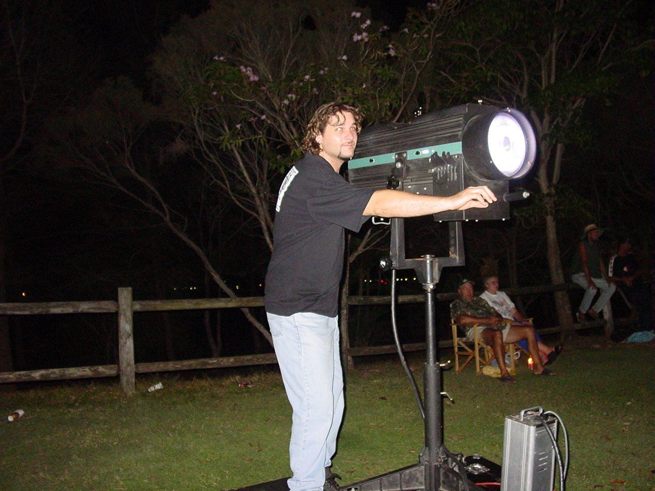 Man Operating A Spotlight Outdoors At Night — Kennedy Amplifier Hire Service In South Mackay, QLD