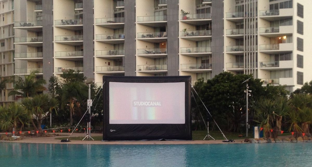 Large Movie Screen By A Pool With Apartment Building In The Background — Kennedy Amplifier Hire Service In South Mackay, QLD