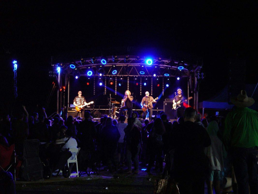 Band Performing On A Stage Lit By Blue Lights At Night — Kennedy Amplifier Hire Service In South Mackay, QLD