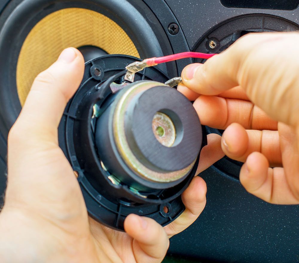 Hands Connecting Wires To A Speaker Component During Repair — Kennedy Amplifier Hire Service In South Mackay, QLD