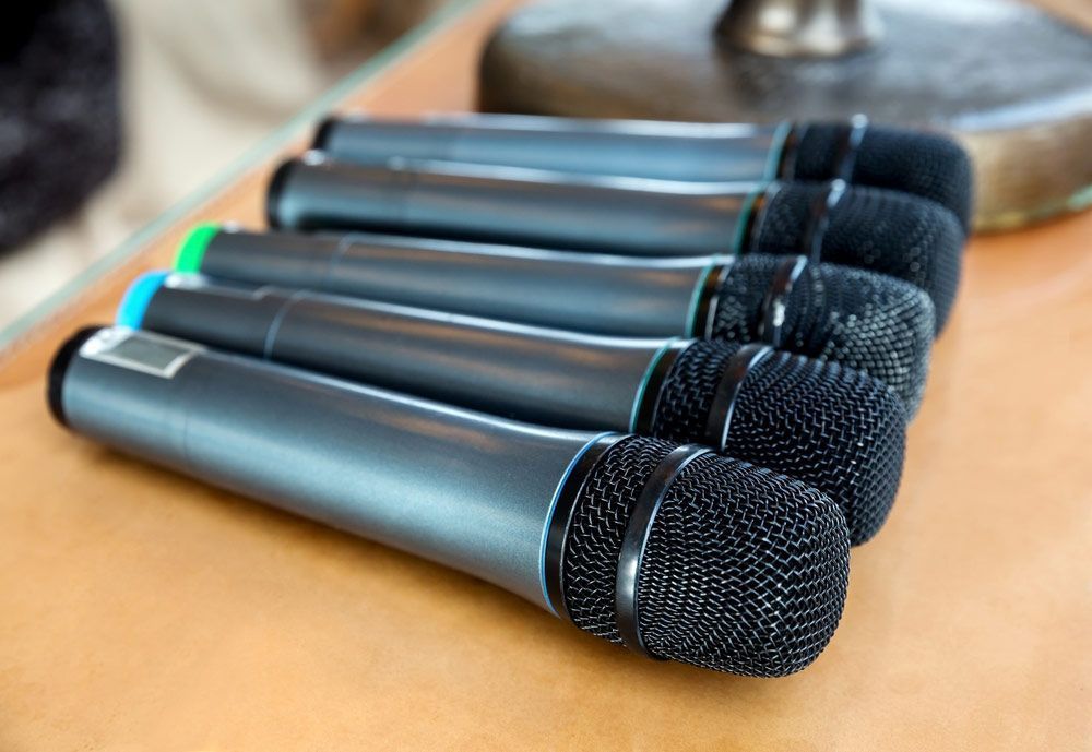 Six Black Handheld Microphones On A Wooden Surface — Kennedy Amplifier Hire Service In South Mackay, QLD