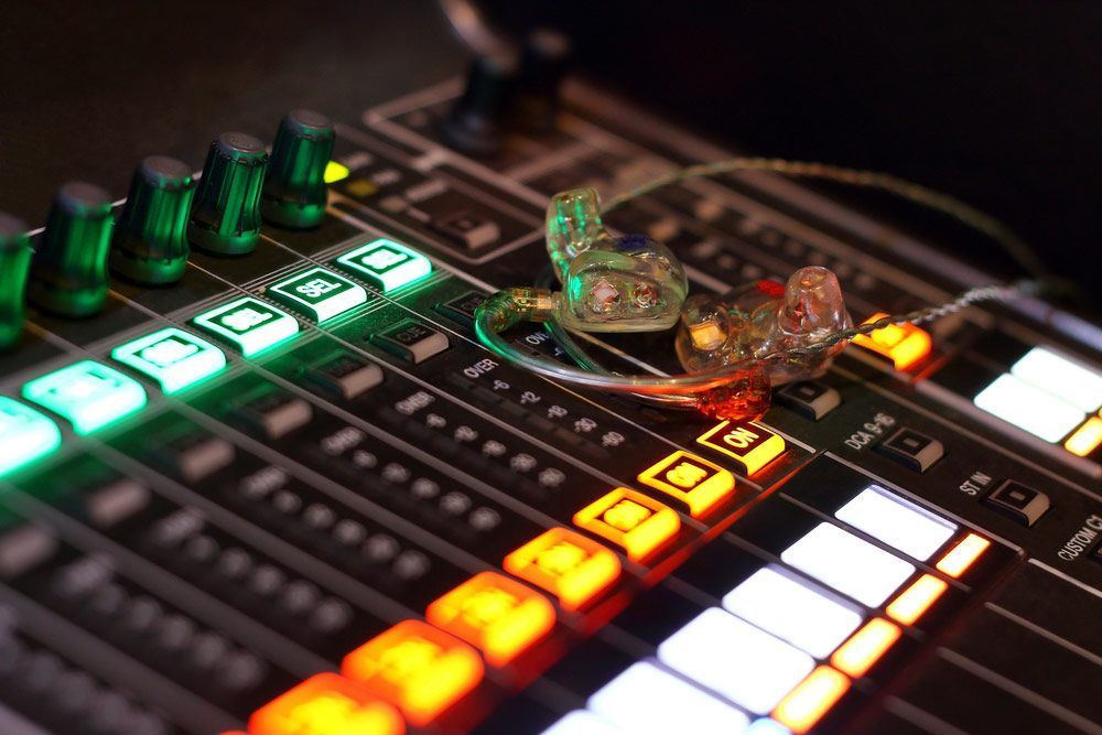 In-ear Monitors Rest On An Illuminated Mixing Console — Kennedy Amplifier Hire Service In South Mackay, QLD