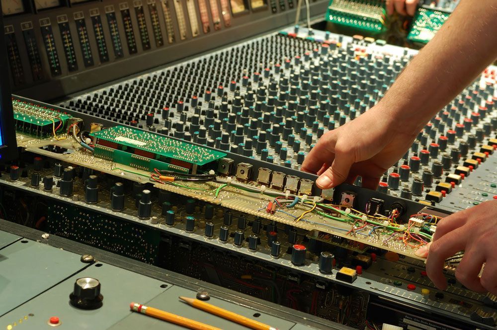 Hands Working On A Large Mixing Console, Removing A Circuit Board — Kennedy Amplifier Hire Service In South Mackay, QLD