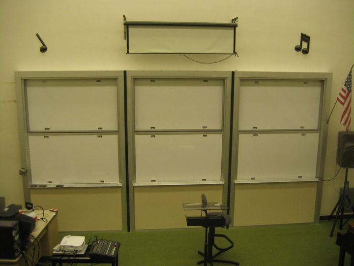Empty classroom with dry-erase boards and a TV mount on the front wall.
