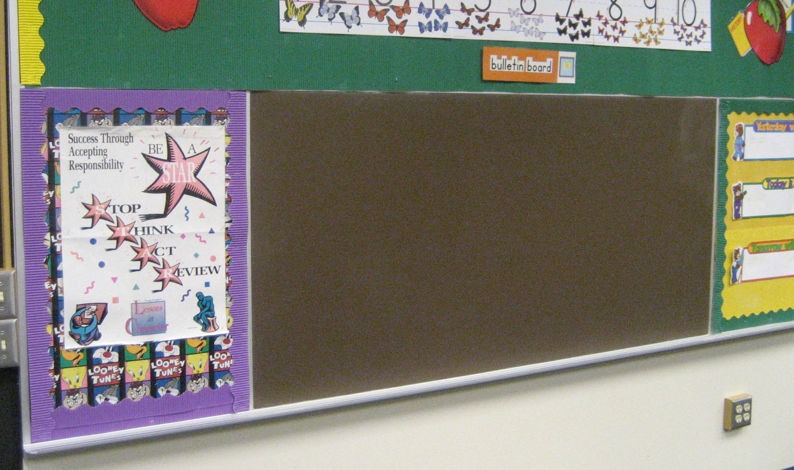 Empty classroom bulletin board with colorful student artwork and border decorations