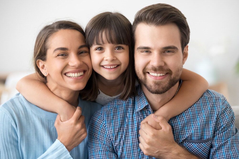 A Family Is Posing For A Picture Together And Smiling For The Camera — The Red Chair Therapy in Blackwall, NSW