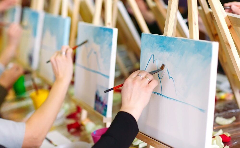 A Group Of People Are Painting On Canvases On Easels — The Red Chair Therapy in Blackwall, NSW