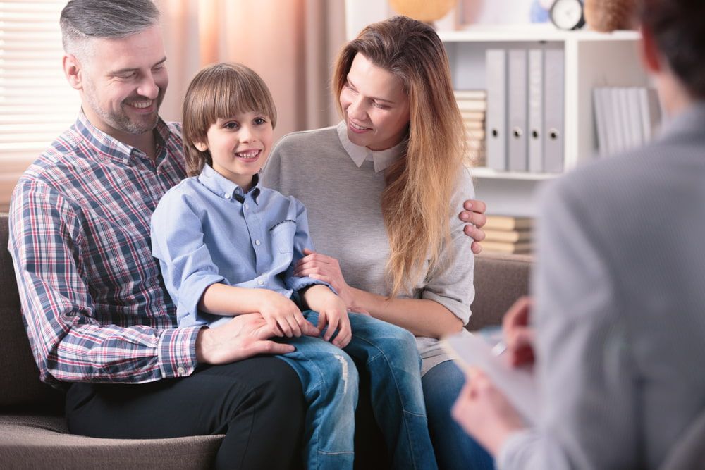 A Family Is Sitting On A Couch Talking To A Counselor — The Red Chair Therapy in Blackwall, NSW
