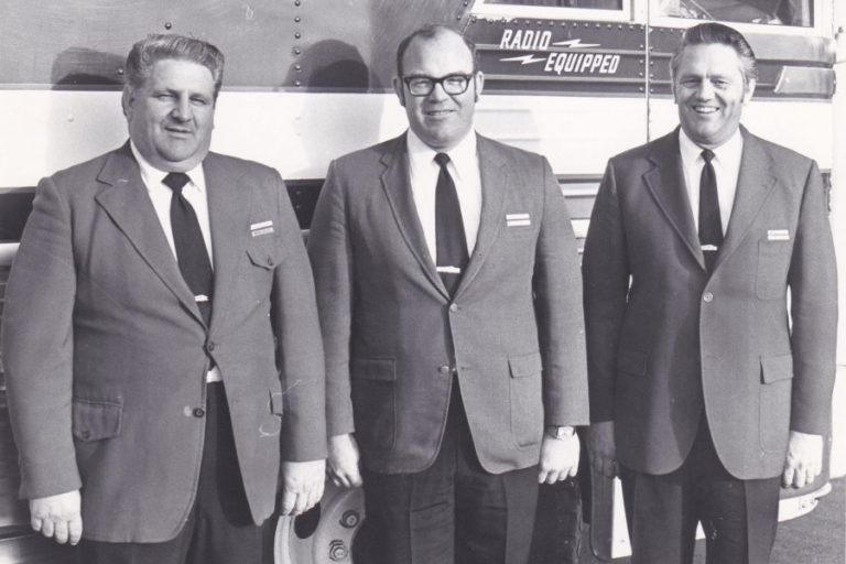 Three men in suits standing indoors beneath a sign reading “Radio Europe.”