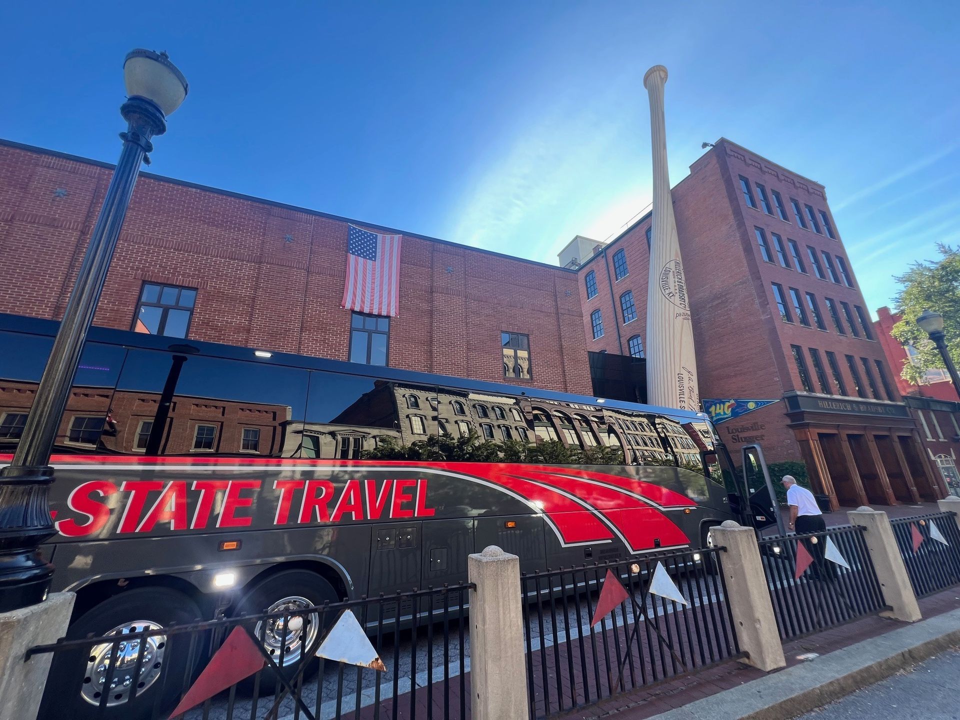 State Travel bus parked by a brick building under a blue sky