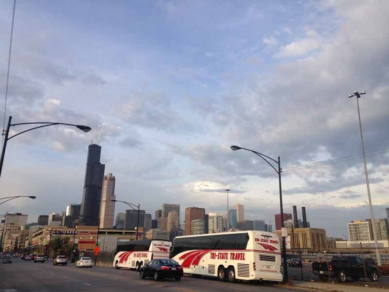 City skyline at dusk with a white taxi and other vehicles on a street under cloudy sky