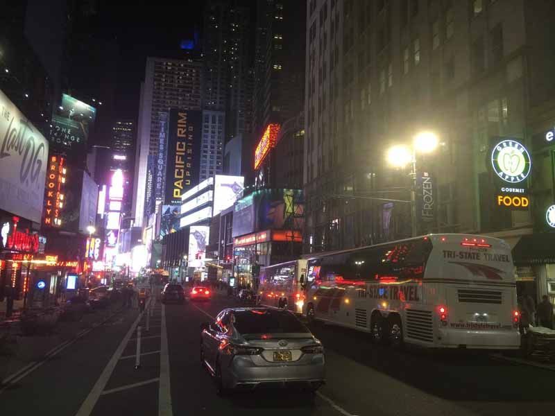 Nighttime city street with heavy traffic, bright billboards, and tall buildings