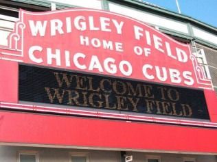 Wrigley Field sign in red and white reading “Home of Chicago Cubs” and “Welcome to Wrigley Field”