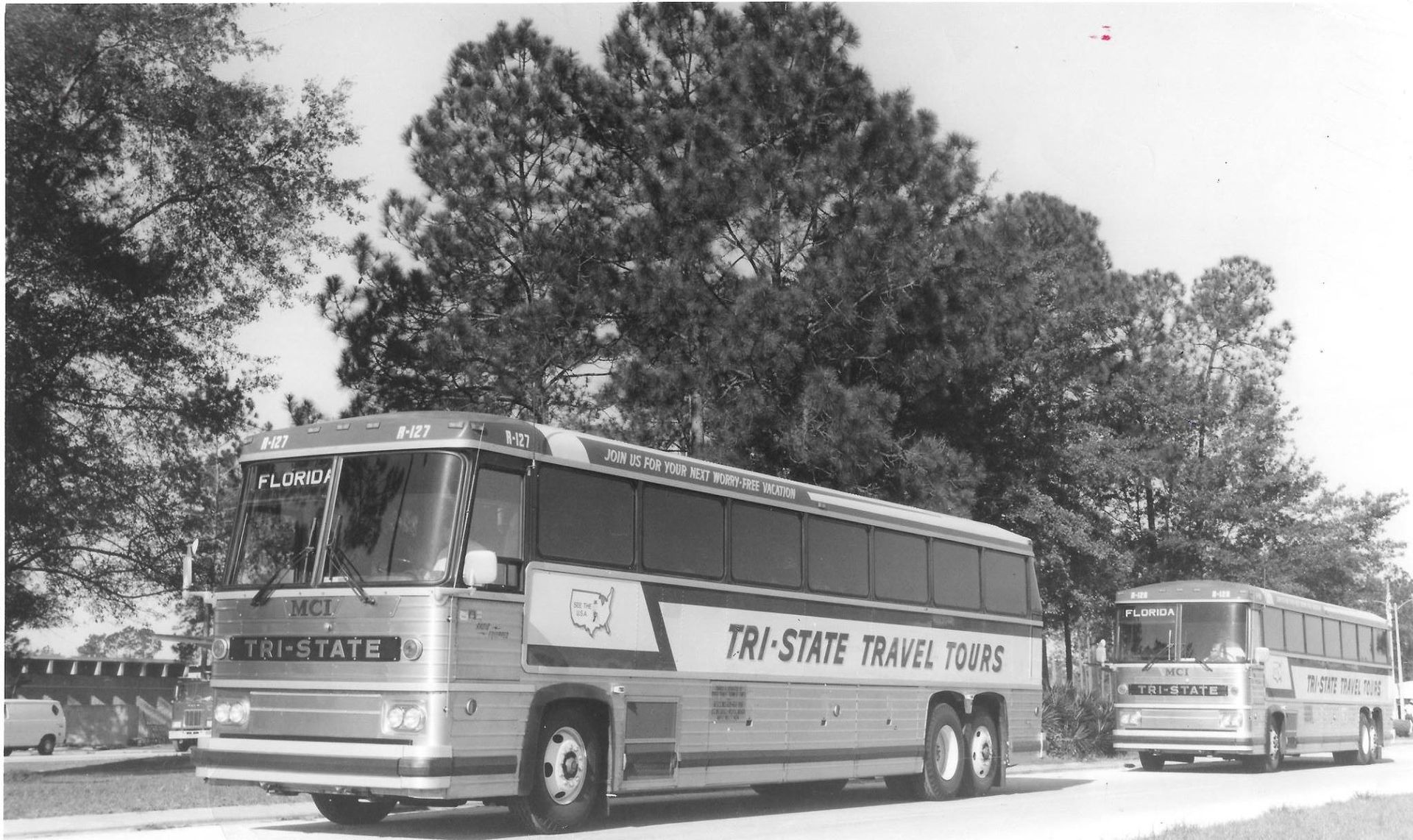 Two vintage buses on a tree-lined road, one labeled Tri-State Transit System.