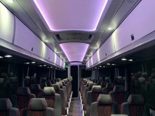 Empty modern bus interior with rows of seats and purple ceiling lights