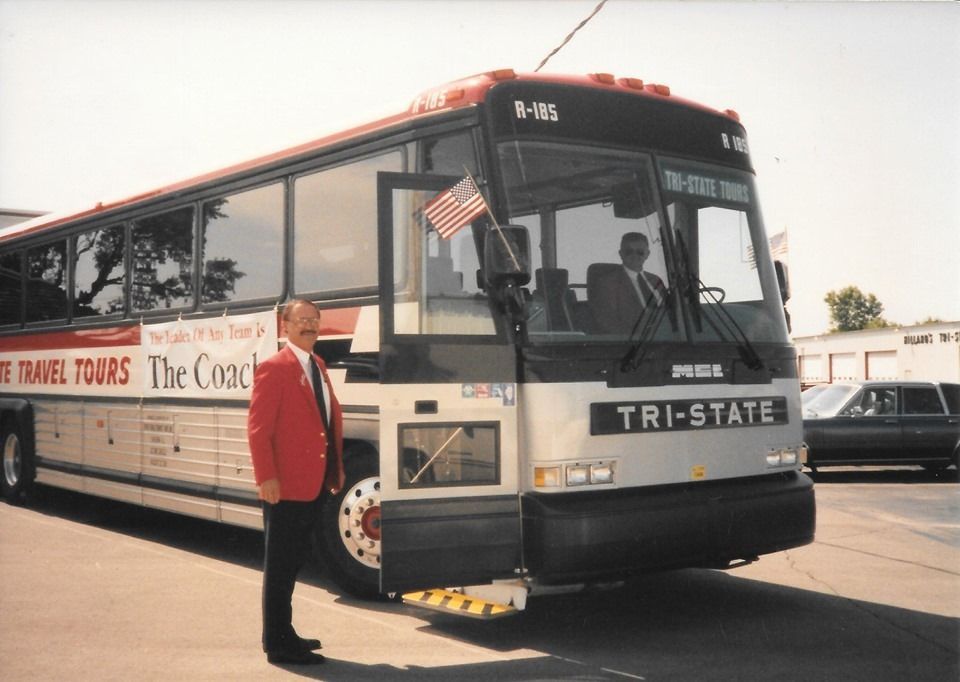 Tri-State tour bus parked curbside with a person standing beside it