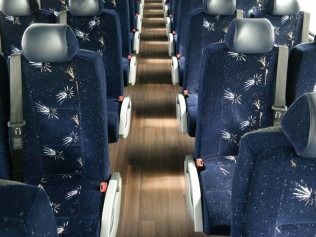 Empty bus aisle with blue patterned seats and wood-look flooring