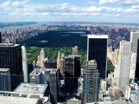 Aerial view of Central Park surrounded by Manhattan skyscrapers under a clear sky.