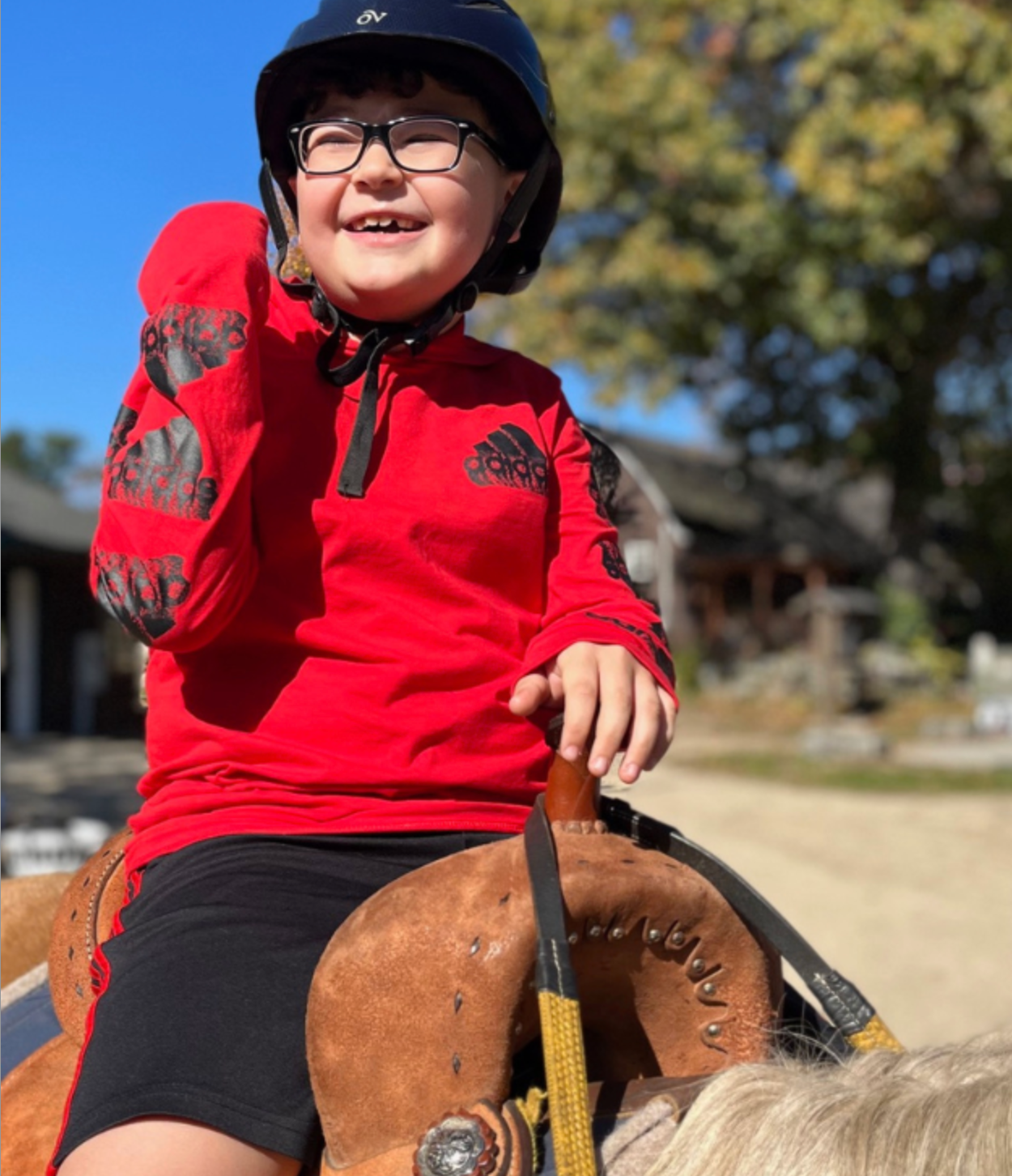 boy in red shirt fist pumps while riding a horse