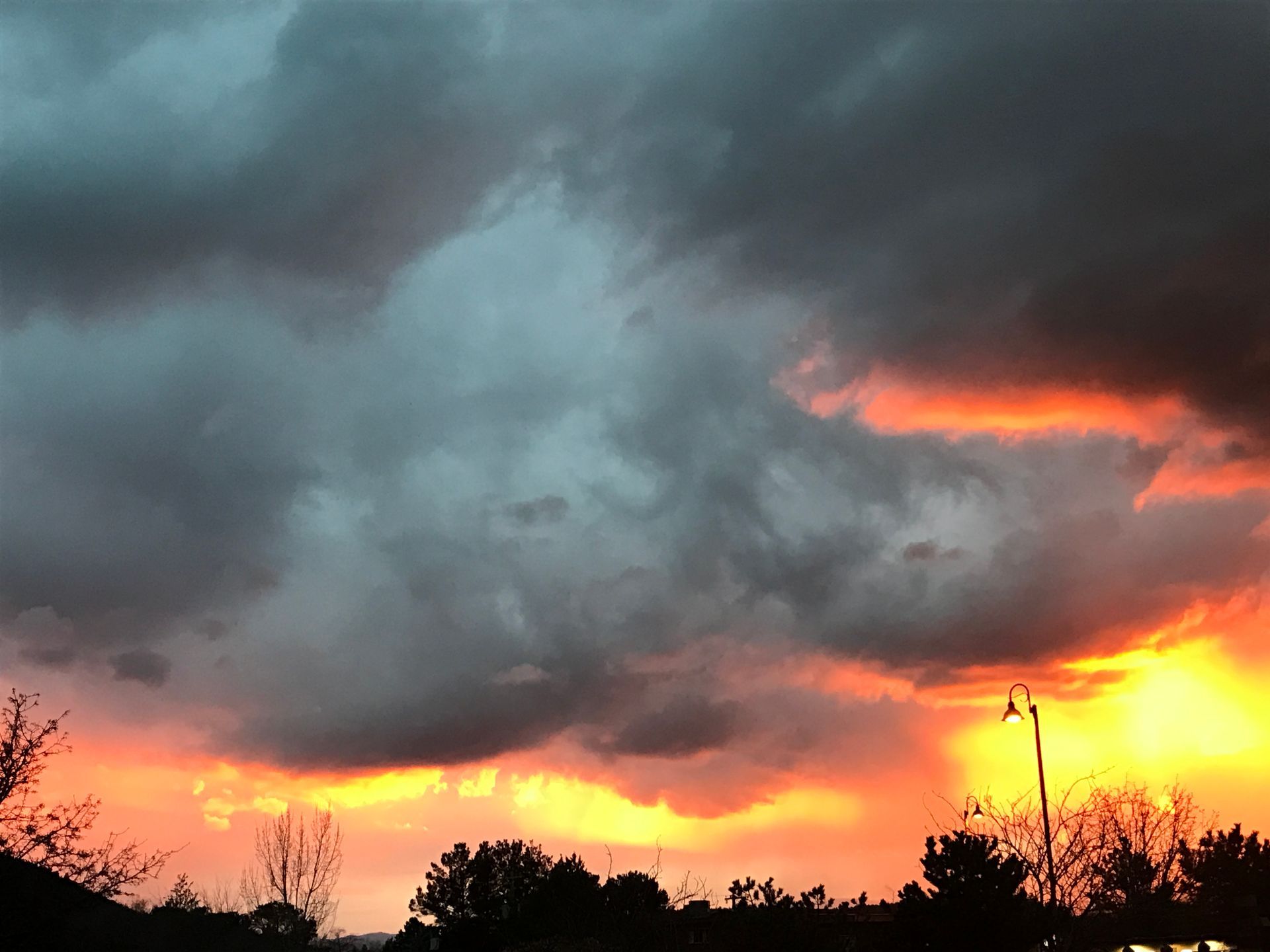 A sunset with a lot of clouds and trees in the foreground