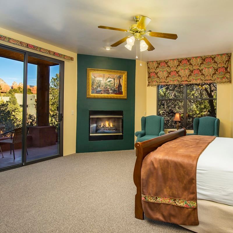 A bedroom with a ceiling fan and a fireplace