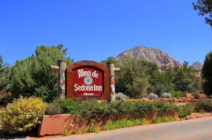 A sign that says alma de sedona inn in front of a mountain