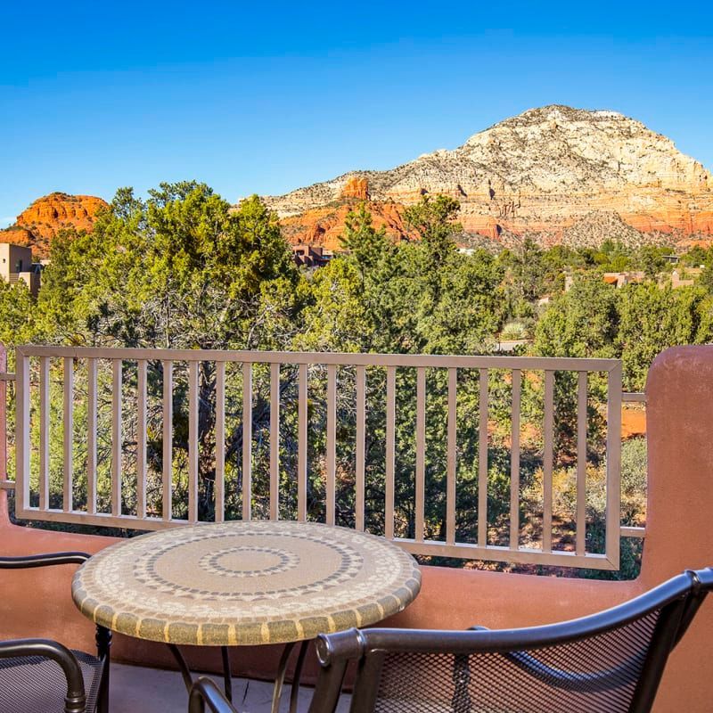 A balcony with a table and chairs and a mountain in the background