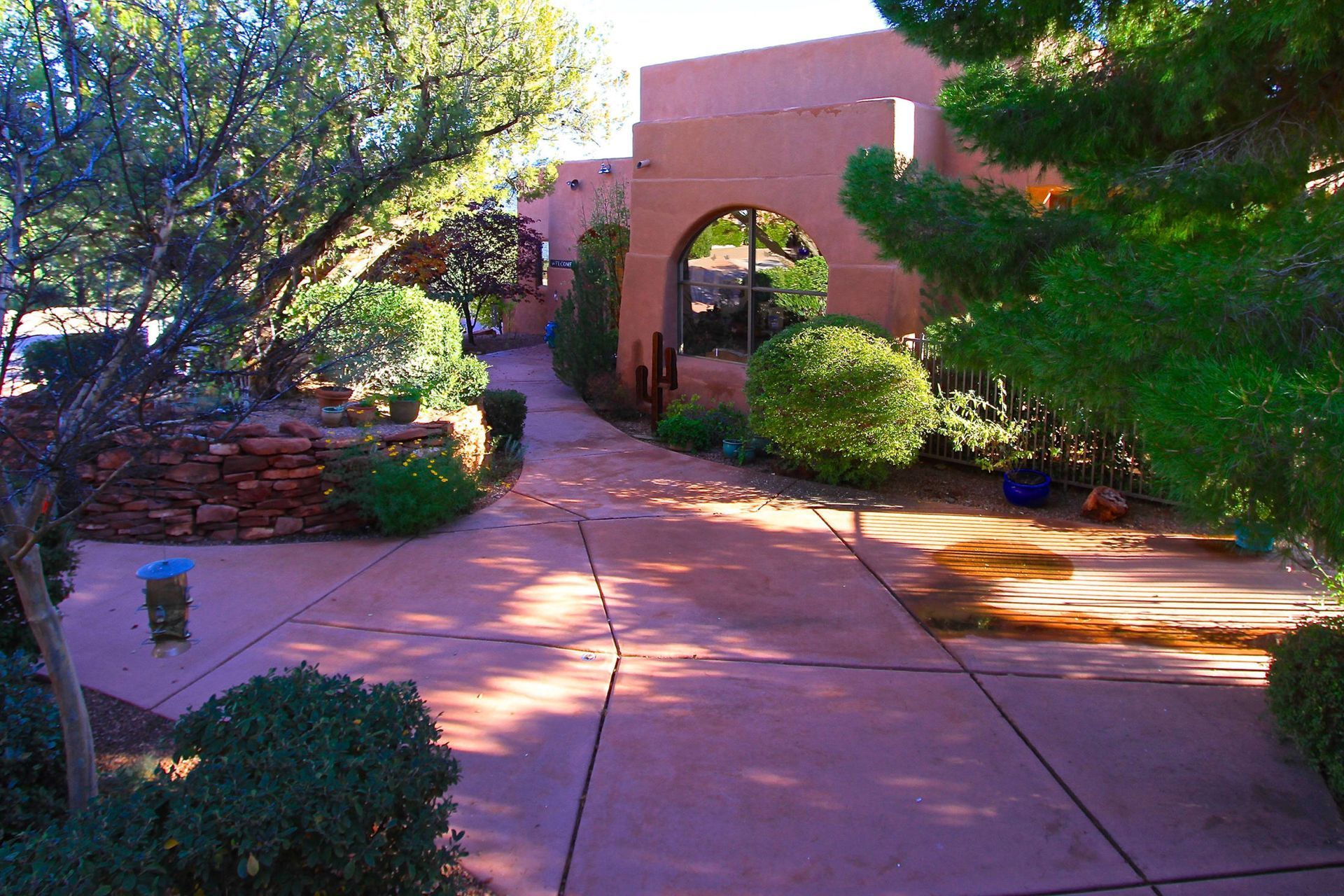 A driveway leading to a building with a stone wall