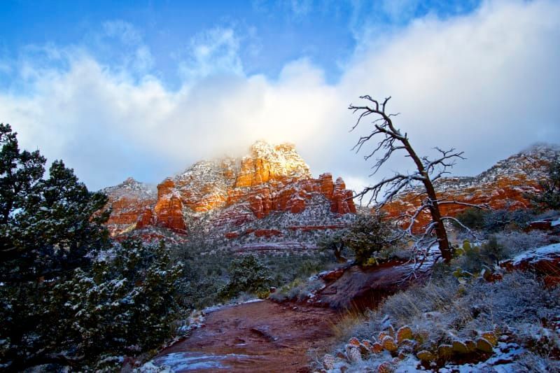 The sun is shining through the clouds on a snowy mountain.