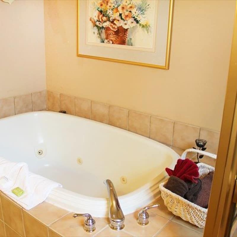 A bathtub with a picture of flowers on the wall above it