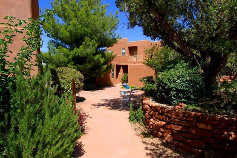 A path leading to a building with a stone wall and trees