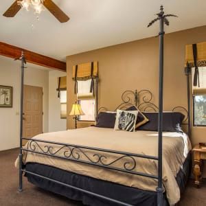 A bedroom with a four poster bed and a ceiling fan.