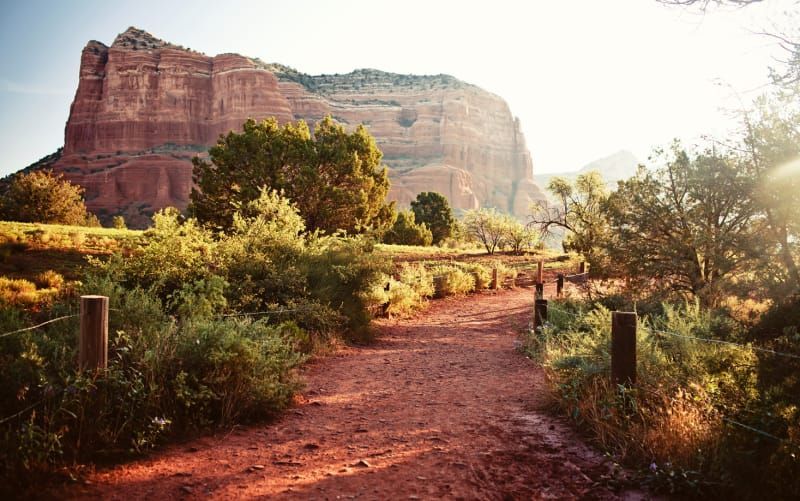 A dirt road in the desert with a mountain in the background.